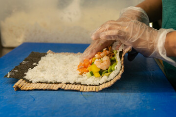 Manos preparando un rollo de Uramaki 