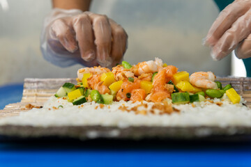 Manos preparando un rollo de Uramaki 