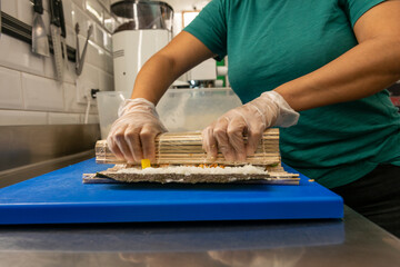 Manos preparando un rollo de Uramaki 