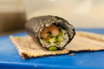 Manos preparando un rollo de Uramaki 