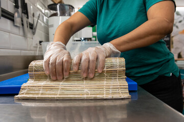 Manos preparando un rollo de Uramaki 