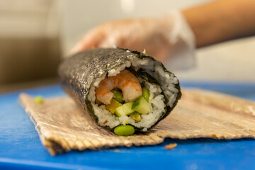 Manos preparando un rollo de Uramaki 