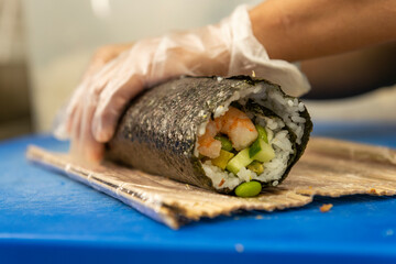 Manos preparando un rollo de Uramaki 