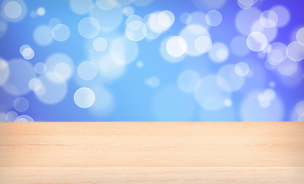 Empty wooden table and bright blue and purple background with bokeh.