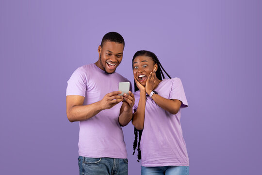 Portrait of surprised black couple using smartphone