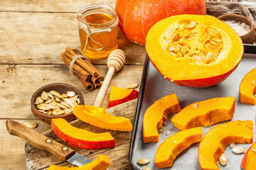 Traditional Autumn wooden background with Hokkaido pumpkin, honey, and spices ready for baking