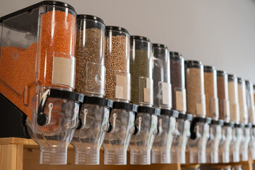 A woman fills a jar with red lentils. Selling bulk goods by weight in an eco store. Trade concept without plastic packaging