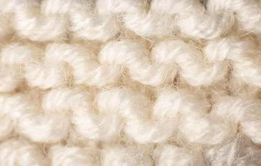 Knitted background of white, beige color. Knitted texture. A sample of knitting from wool. Knitting Pattern.knitting pattern from wool. warm winter clothes, scarf, close-up. Wallpaper, macro