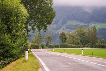 Fototapeta na wymiar Curving asphalt road in the highlands near an alpine village in the summer, Europe, Austria