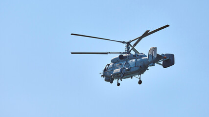 Navy helicopter flying against blue sky background, copy space. One rotary wing aircraft, side view