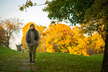 Lady is waking a path in the park during a beautiful autumn afternoon