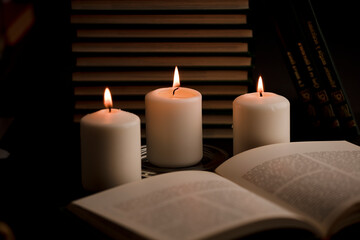 home study table with candles with flame and reading book, (focus on candle).