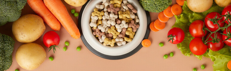 Dry dog vegan vegetarian food concept. Raw vegetables and green near bowl with pet feed on brown...