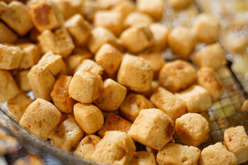 Deep fried tofu over boil of oil in metal pan.