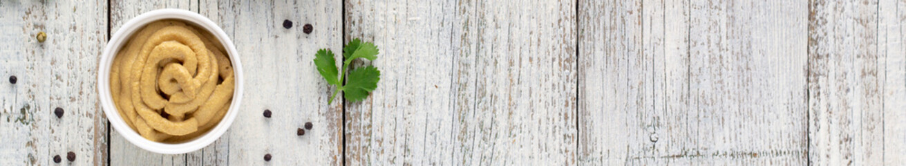 banner of mustard with spices on white wooden background.