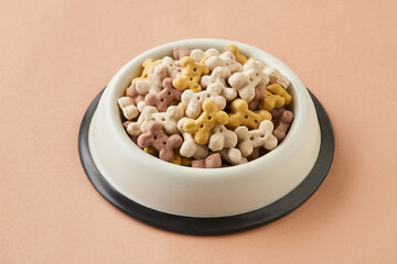 Dry dog food in bowl on brown background
