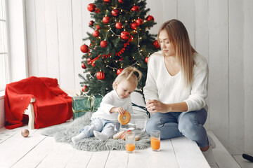 Obraz na płótnie Canvas Mother with little daughter sitting near Christmas tree and and go donuts.