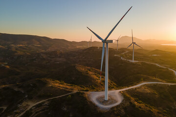 Wind turbines at sunrise. Wind farm generating green power with carbon neutral