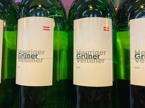Viersen, Germany - June 9. 2021: View on bottle labels with logo lettering of heuriger green veltiner in shelf of german supermarket (focus on center of right bottle label)