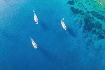 Sailing yachts anchored in the bay with clear and turquoise water. Aerial drone view