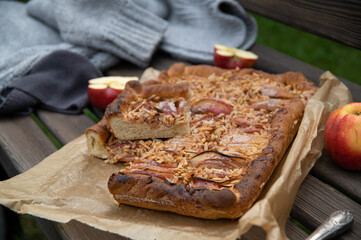 fresh baked autumnal apple pie with almonds served outside on a wooden bench in the garden