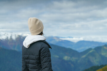Back view of young woman on top of mountain