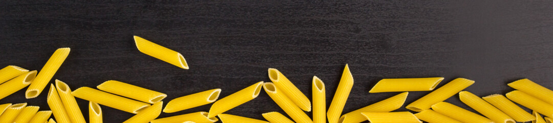 banner of Border of A pile of penne pasta on black background with copyspace