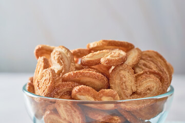 Palmier puff pastry cookies or elephant ears in a bowl of caramelized and crunchy pastry.
