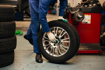 Fototapeta na wymiar Auto mechanic balances the car wheel on the wheel balancer