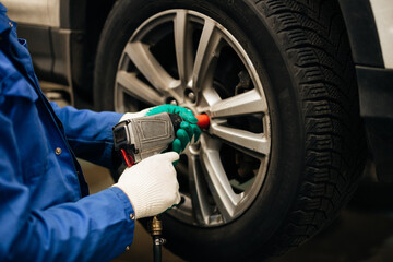 Auto mechanic balances the car wheel on the wheel balancer