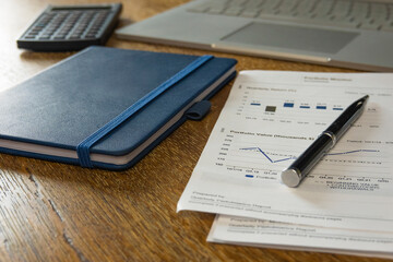 Laptop, calculator, notebook, and financial papers on a desk