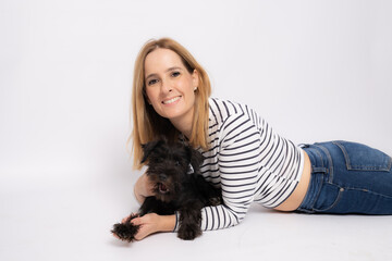 Young smiling woman lying on the floor embracing her dog isolated over white background.