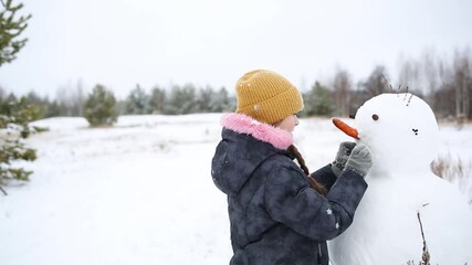 child sculpts makes snowman outdoors. kids fun in winter.