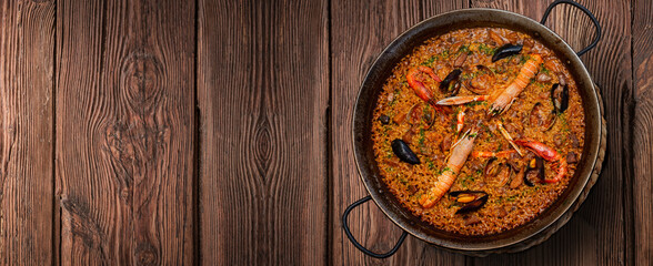 Seafood paella on rustic wood on banner format
