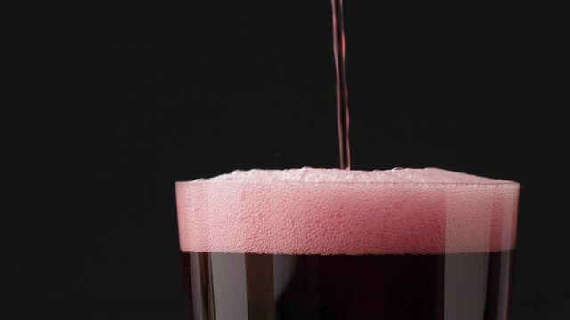 Slow motion pour red berry drink in tumbler glass