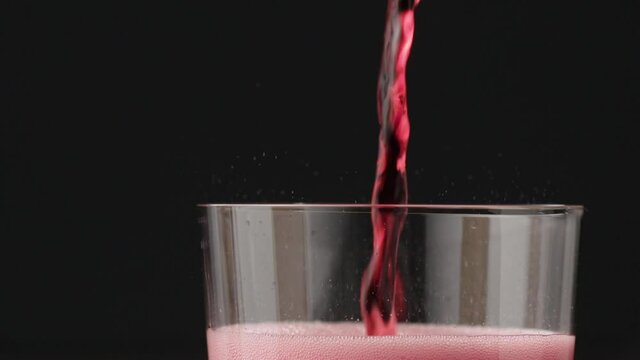 Slow motion pour red berry drink in tumbler glass
