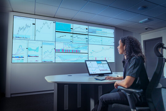UK, York, Woman studying trading charts on multiple screens