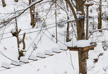 Rope park covered with snow is located in the trees in a desert forest in winter