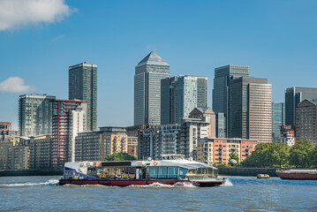 Fototapeta na wymiar Scenic view on a sunny day with blue skies on office buildings, skyscrapers, River Thames, yacht, marina and residential buildings in the business district of London, UK.