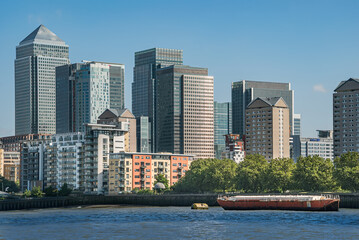 Fototapeta na wymiar Scenic view on a sunny day with blue skies on office buildings, skyscrapers, River Thames, yacht, marina and residential buildings in the business district of London, UK.