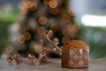 Italian Christmas cake Panettone, blurred christmas tree background.