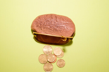 Coin purse. Wallet on a green background. Scattered coins. The color of the trend.The concept of poverty.