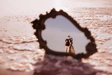 girl and a guy on the shore of a pink salt lake