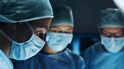 Multiracial team of professional medical surgeons performs the surgical operation in a modern hospital. Doctors are working to save the patient. Medicine, health, cardiology and transplantation. - Powered by Adobe