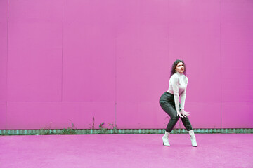 Fototapeta na wymiar Dancing glamorous girl perform sexy dance outside by pink wall with copy space for ad. Female active urban lifestyle