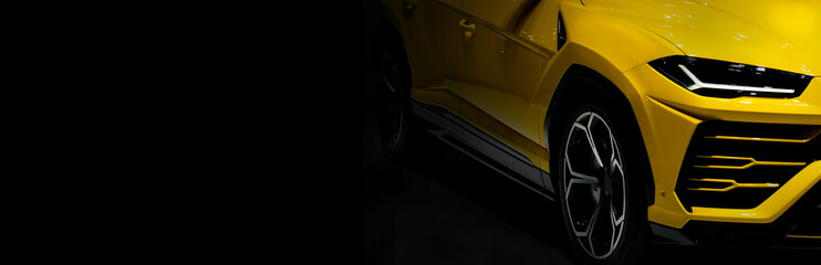 Front view of the LED headlights yellow super car on black background, free space on left side for text.