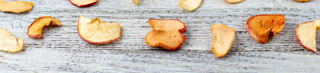 banner of Pattern of a pile of dried apples in slices on a white wooden background. Dried fruit chips. Healthy food