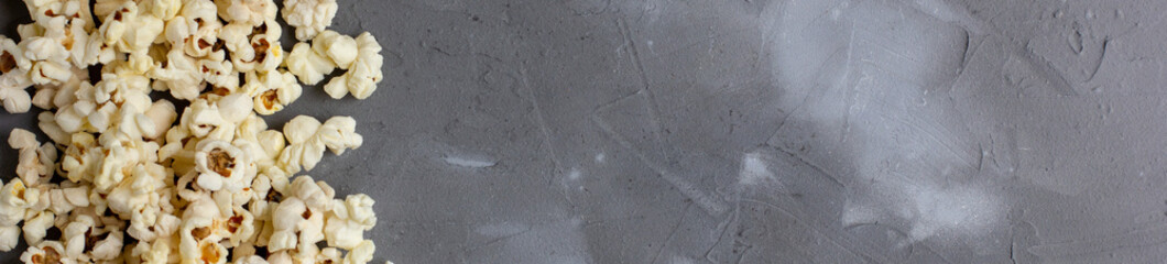 banner of Border of fresh popcorn on grey stone background. Top view