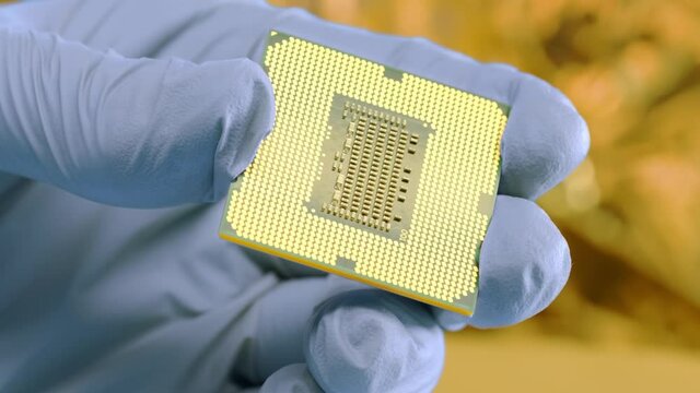 The technician scientist holding the innovation central processor in the hand in the in the nanotech laboratory. Powerful chip for space ships in the military lab against the gold foil background.