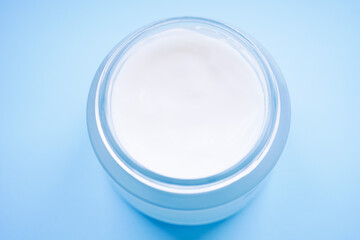 Open jar of cream on a pale blue table